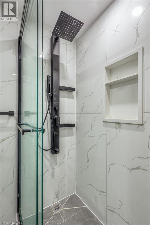Shower enclosure featuring a matte black rain shower head, hand-held shower, and body jets
