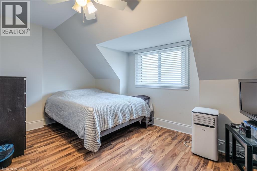 Attic room featuring sloped ceilings, wood-finish flooring, and a window with horizontal blinds