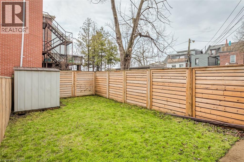 Enclosed backyard featuring horizontal-slat wood fencing, a verdant lawn, and a storage shed