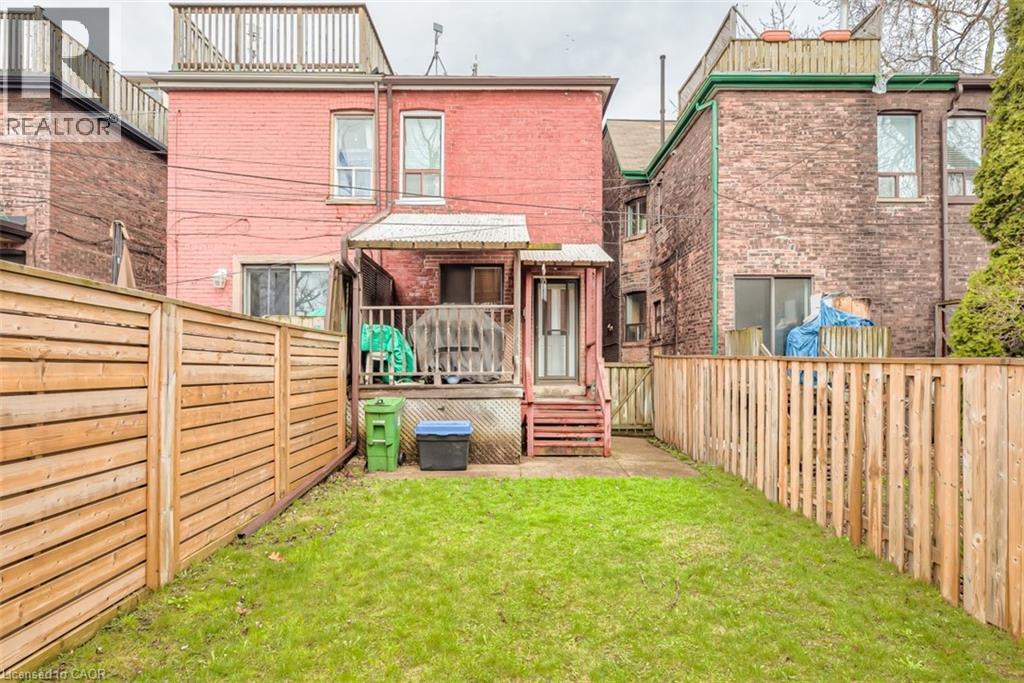 Expansive backyard featuring a green lawn, wood privacy fencing, and a raised wooden deck with stairs
