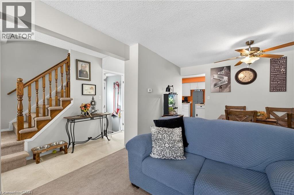 Inviting open concept living area with carpeting, a ceiling fan, and staircase with wooden banister