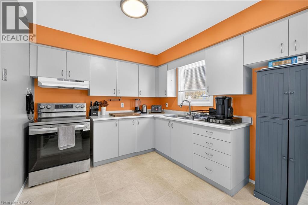The kitchen features light-colored cabinetry, a stainless steel range with an overhead vent, and a window above the sink
