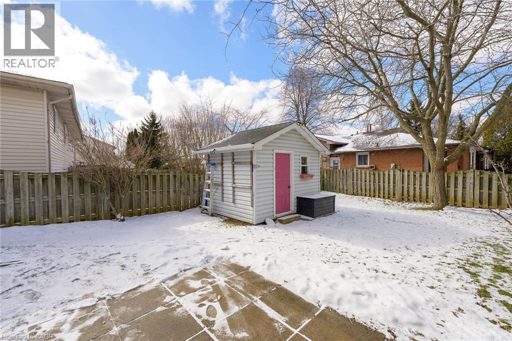 The property features an extensive yard with a lawn, a wooden fence, and a storage shed with a vibrant pink door