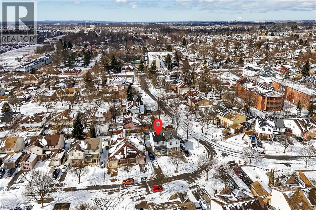 Aerial view showcasing the property within a residential setting, surrounded by other structures and bare trees, all under a blanket of snow