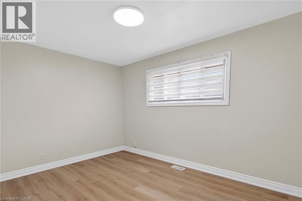 Neutral-toned room featuring wood-finish flooring, a contemporary flush-mount ceiling light, white baseboards, and a window with horizontal blinds