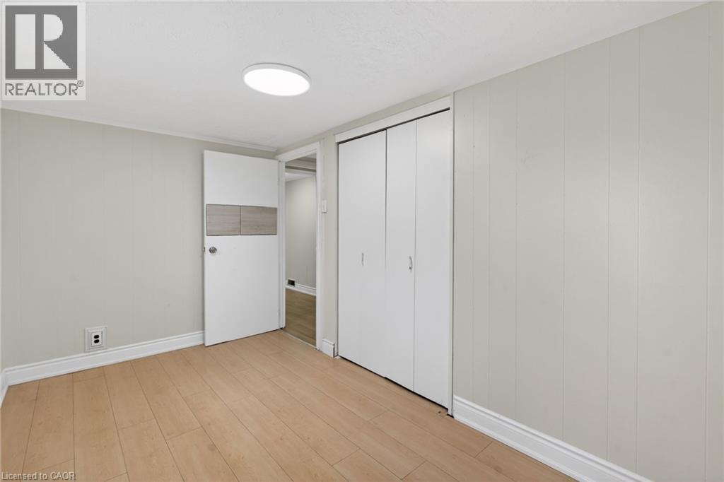 Room with wood-finish flooring, light grey walls, and white trim