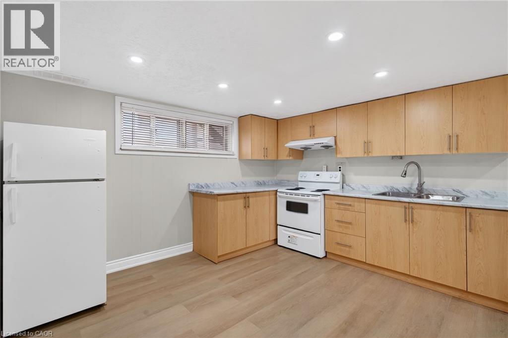 Kitchen featuring light wood-finish cabinetry, white appliances, and marble-look countertops