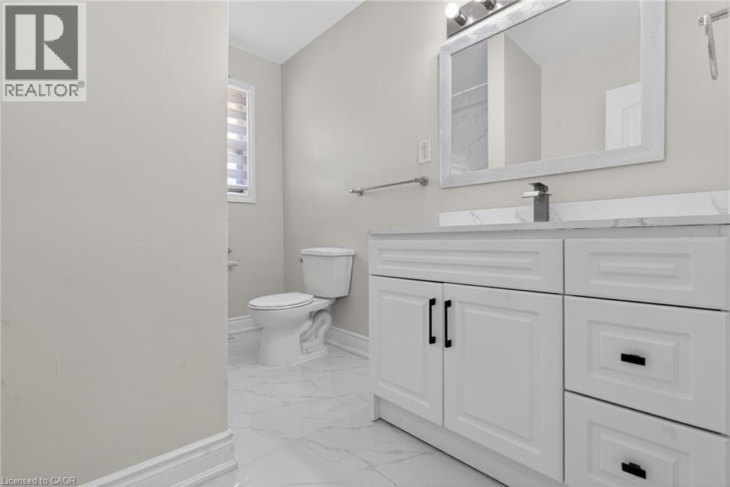White vanity with black hardware, a rectangular mirror, and a modern single-handle faucet, set against light-toned walls and marble-look floor tiling