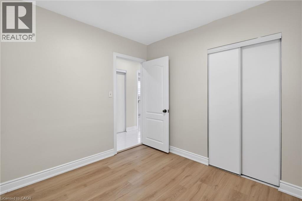 Room featuring wood-finish flooring, light-toned walls, white baseboards, and a white sliding closet door