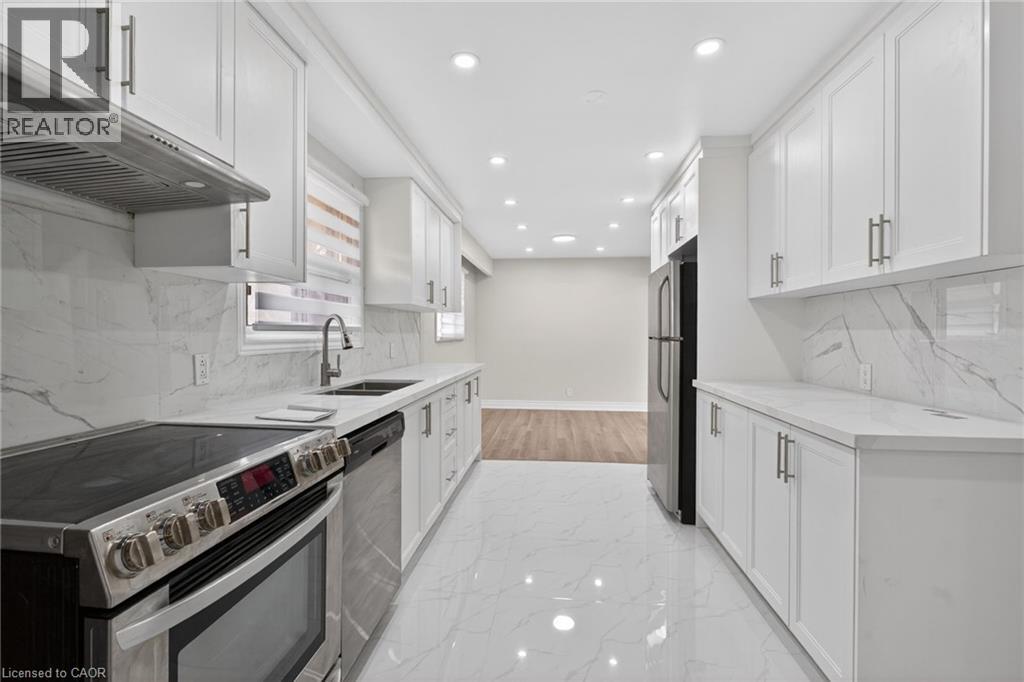 Modern kitchen featuring white shaker cabinetry, stainless steel appliances, white countertops, and a white marble-patterned backsplash