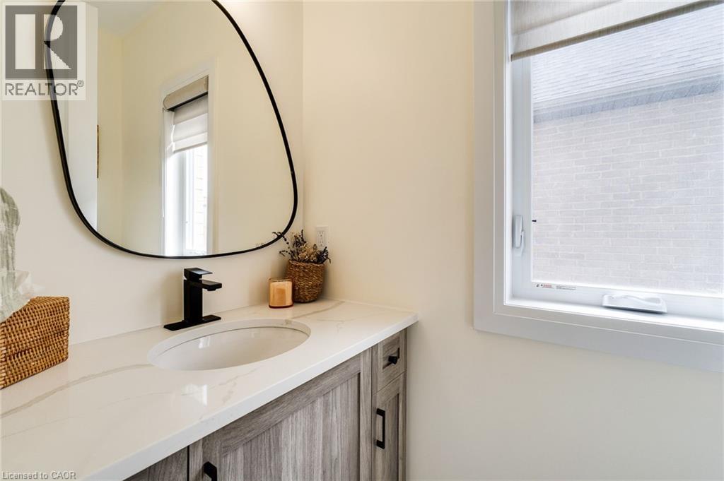 Bathroom vanity featuring wood-finish cabinetry, a white countertop, and an undermount sink with a matte black faucet