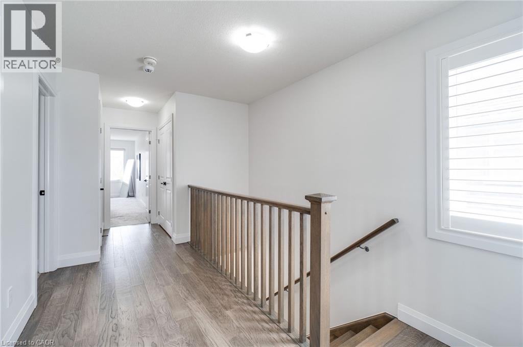 Contemporary hallway featuring wood-finish flooring, white walls, and recessed lighting
