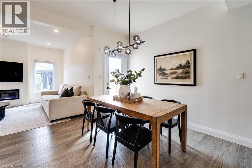 Open concept living and dining area featuring wood-finish flooring, a contemporary linear chandelier, an electric fireplace, and a picture window
