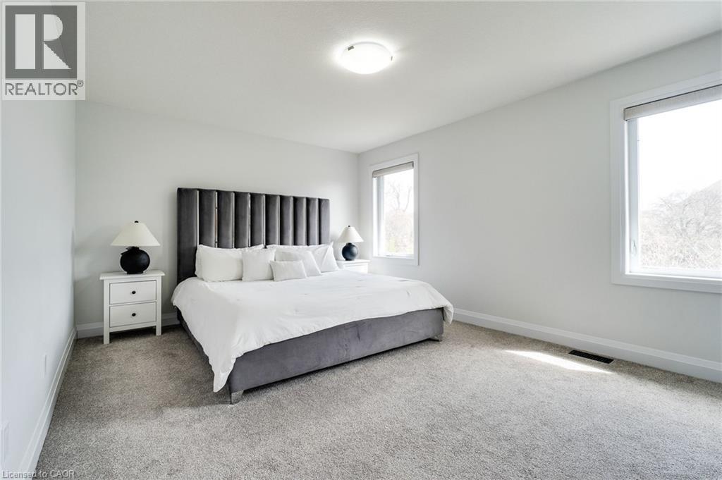 Bright room featuring light gray carpeting, neutral wall finishes, and two large windows with roller shades