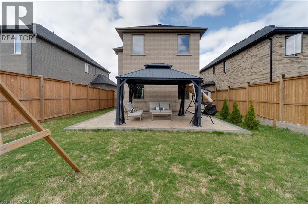 Expansive backyard featuring a manicured lawn, full wood fencing, and a concrete paver patio with an integrated gazebo structure