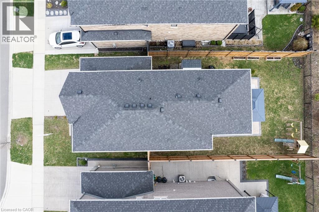 Property featuring a gray shingle roof, a paved driveway, a grass lawn, and wood fencing