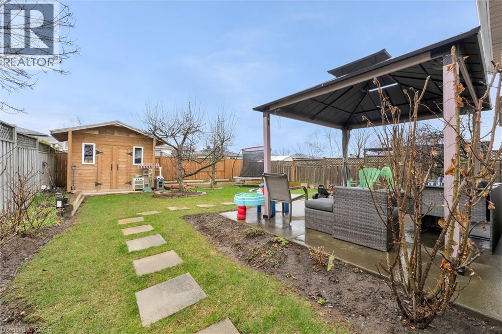Fenced backyard featuring a patio, an outdoor hangout area, a gazebo, a trampoline, and a storage unit