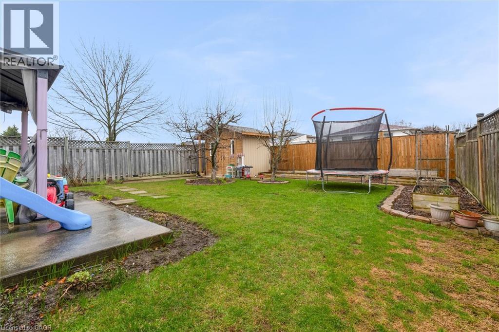 Fenced backyard with a trampoline and a patio area