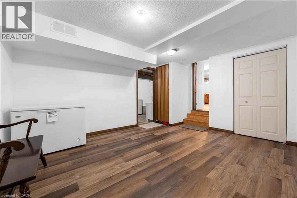 Finished basement with a textured ceiling, dark wood-style floors, and fridge