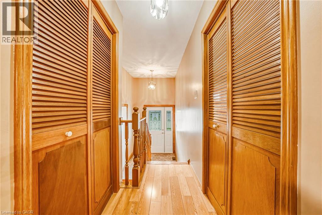 Hallway featuring wood-finish flooring and louvered bifold closet doors