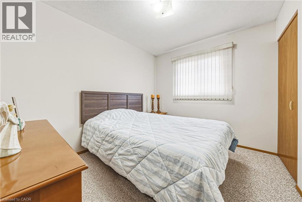 Carpeted room featuring a window with vertical blinds, a wooden headboard, and a built-in closet with a wood-finish door