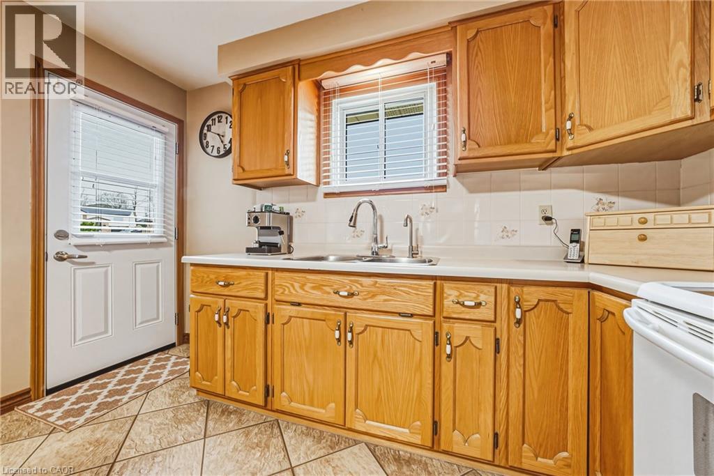 Kitchen featuring wood-finish cabinetry, a double basin sink, and a white tile backsplash