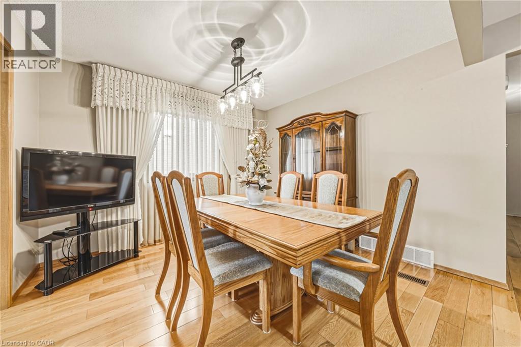 Dining area featuring wood-finish flooring, a contemporary chandelier, and window treatments