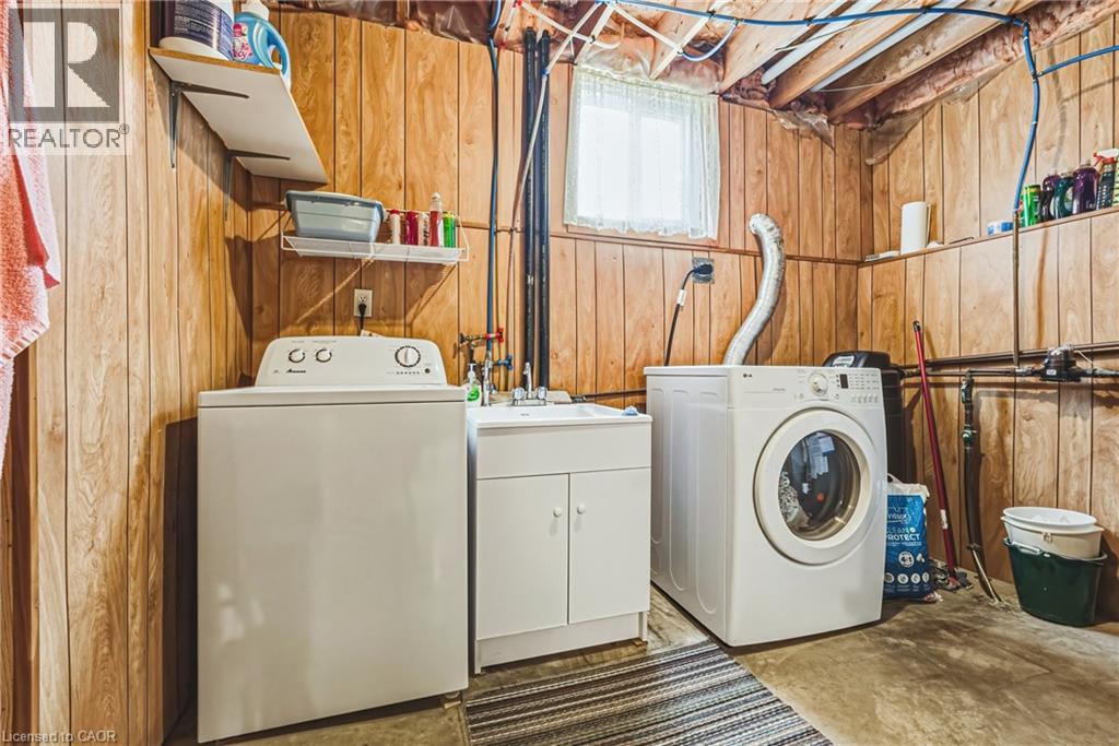 Dedicated laundry area featuring wood-panel walls, a utility sink with built-in cabinetry, and a window for natural light