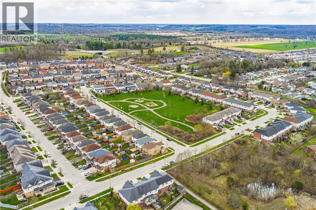 Residential neighborhood featuring a central green space with playground equipment, paved streets, and a mix of detached and attached housing