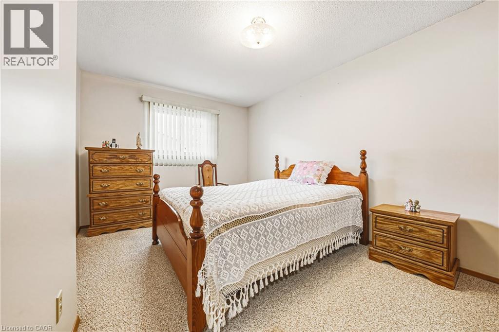 Carpeted bedroom featuring a window with horizontal blinds, light-toned walls, and a ceiling-mounted light fixture