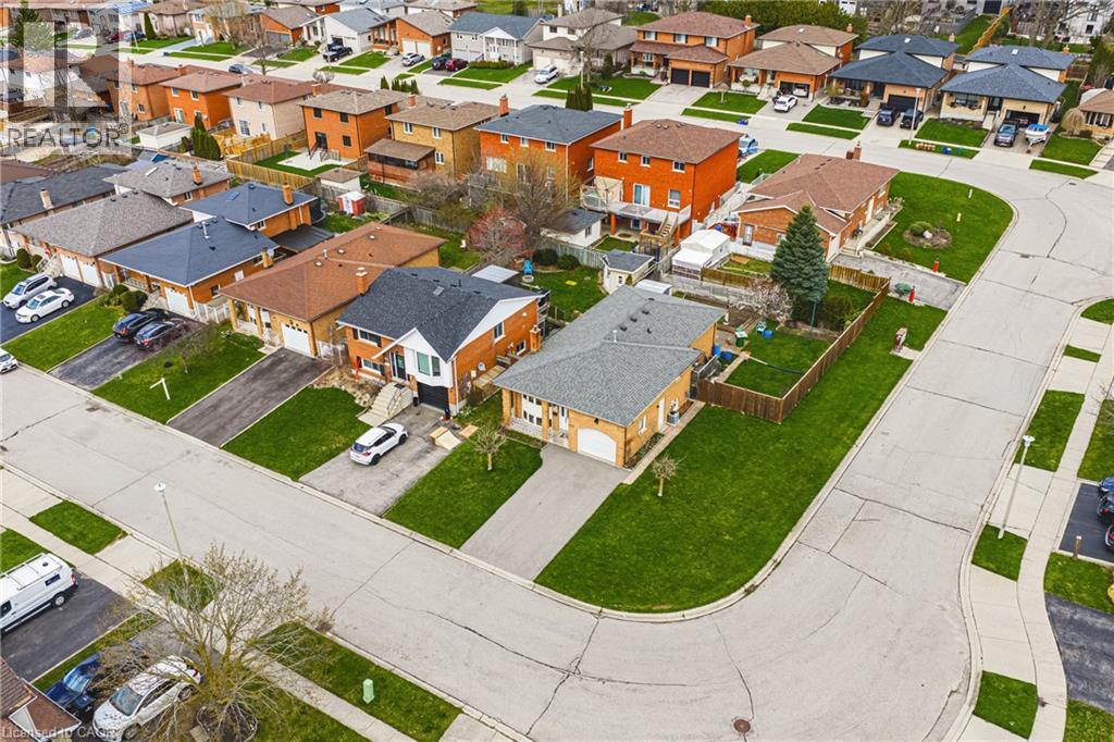 Residential street featuring detached properties with brick exteriors, asphalt driveways, and green lawns