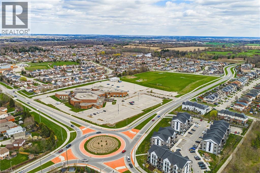 Aerial perspective of a developed residential area featuring a circular road intersection, multiple residential structures, and a large institutional building with an expansive parking area