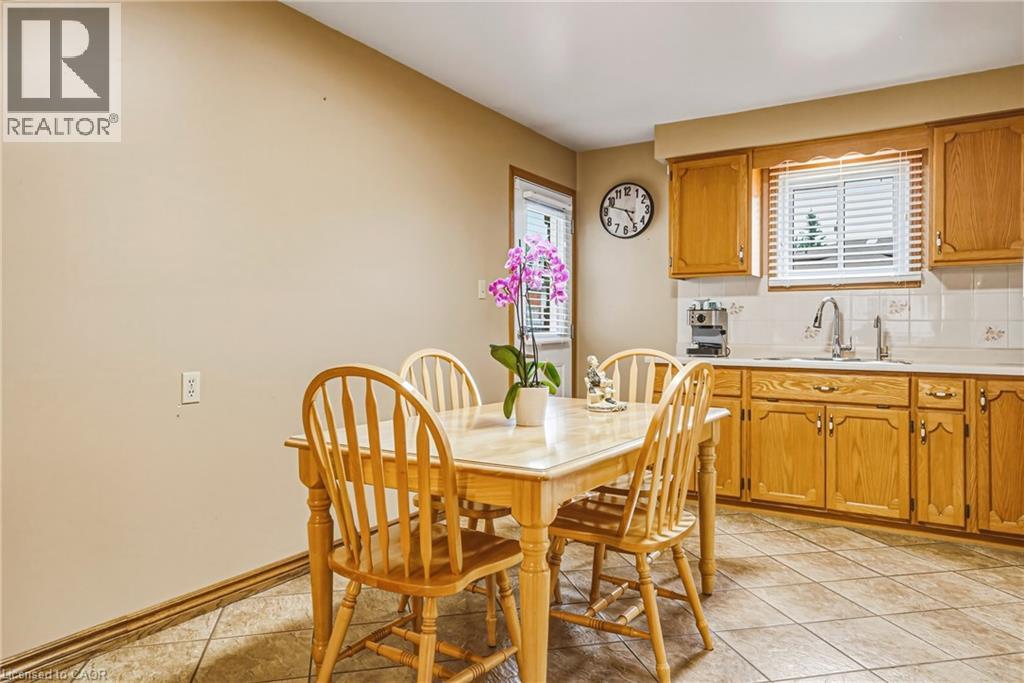 Kitchen featuring wood cabinetry, white tiled backsplash, and a stainless steel sink with a gooseneck faucet