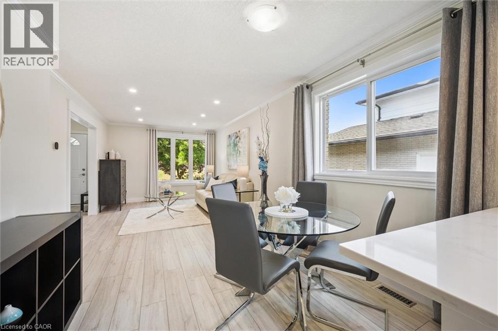 Open concept living and dining areas featuring wood-finish flooring, white crown molding, recessed lighting, and large windows