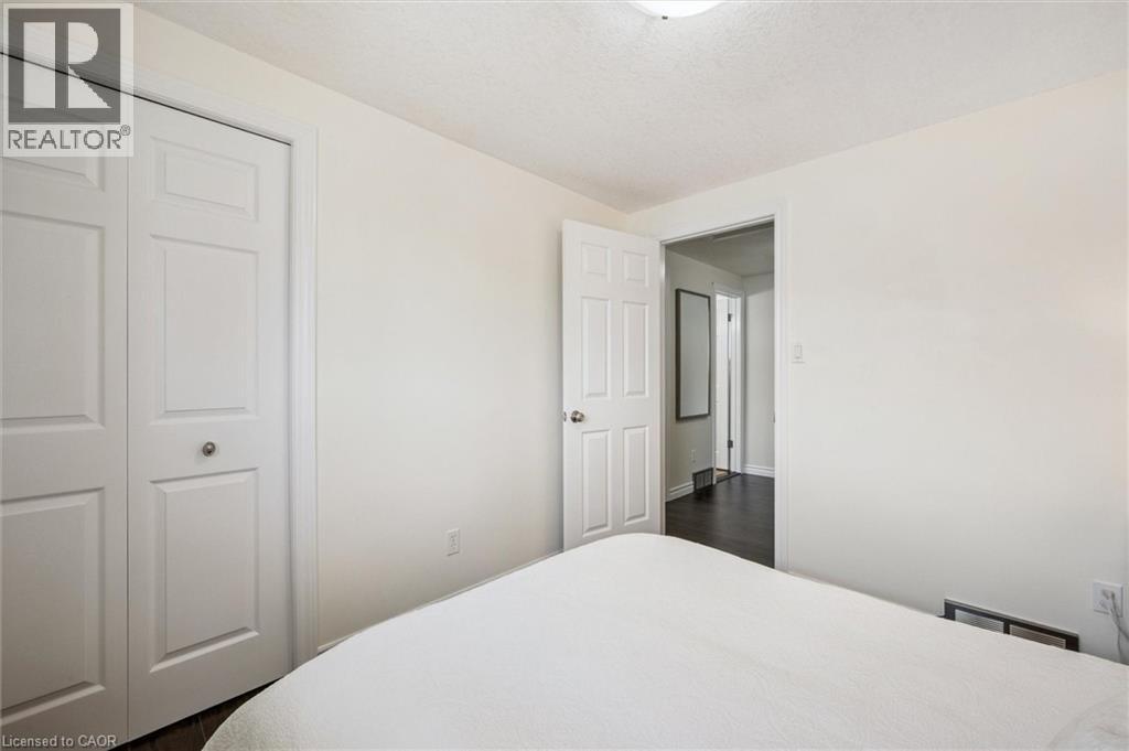 Bedroom featuring light-toned walls, bi-fold closet doors, and dark wood-finish flooring
