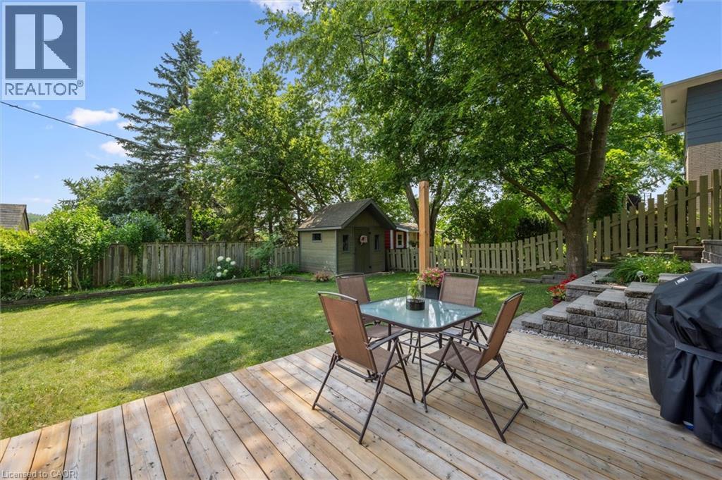 Expansive outdoor space featuring a spacious wood deck, manicured lawn, and mature trees