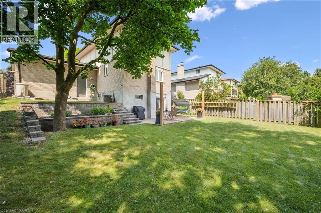 Expansive backyard featuring a large grass lawn, mature trees, and wood fencing