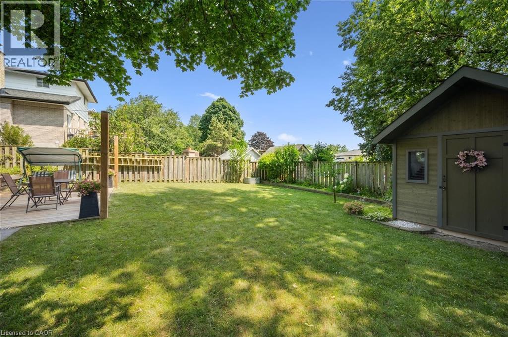 Expansive fenced backyard featuring a grassy lawn, a wooden deck, and a detached storage shed with a gabled roof