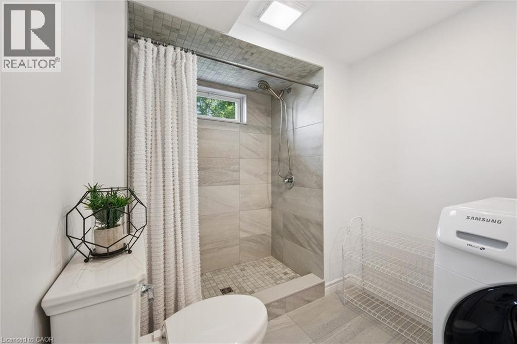 Shower with light grey tile surround, recessed window, and white shower curtain