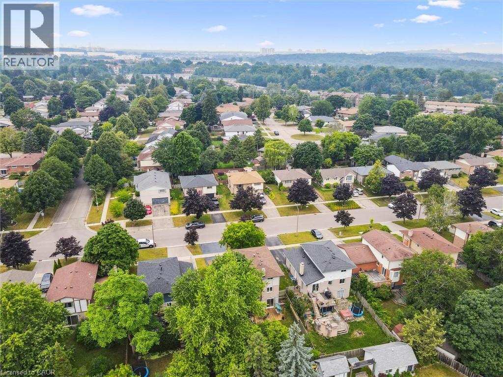 Aerial overview showcasing a residential neighborhood with numerous detached homes, mature trees, and paved streets
