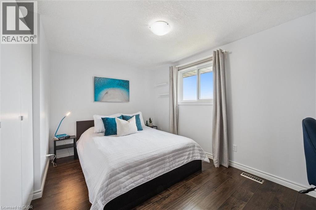 Bedroom featuring dark wood-finish flooring, a double-paned window, and a built-in closet with white doors