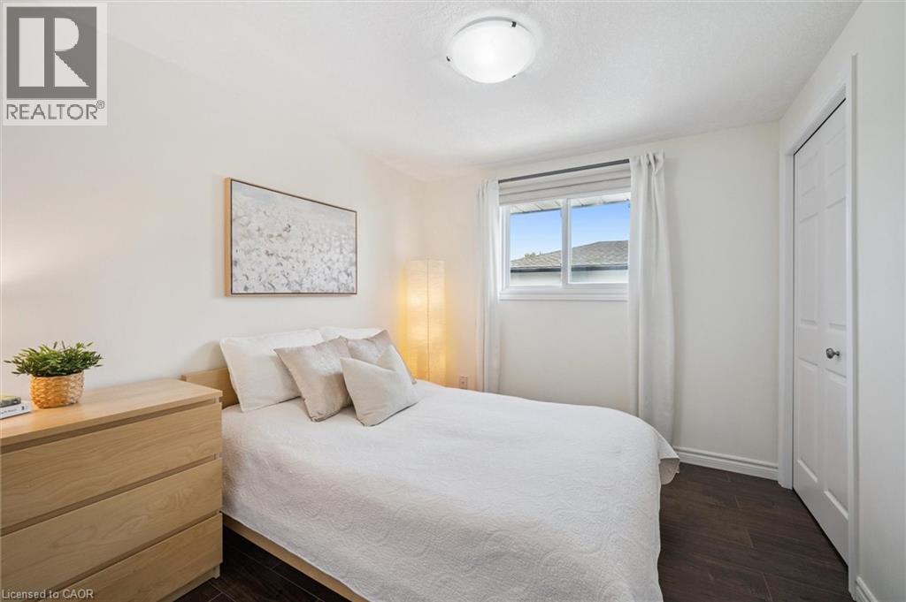 Bright room featuring dark wood-finish flooring, white walls, and a window with white blinds and curtains