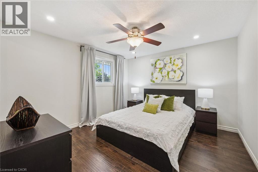 Bedroom featuring wood-finish flooring, a ceiling fan with integrated lighting, recessed lighting, and a window with white trim