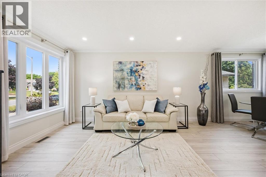 Bright living area featuring light-toned wood-finish flooring, recessed ceiling lighting, and large windows