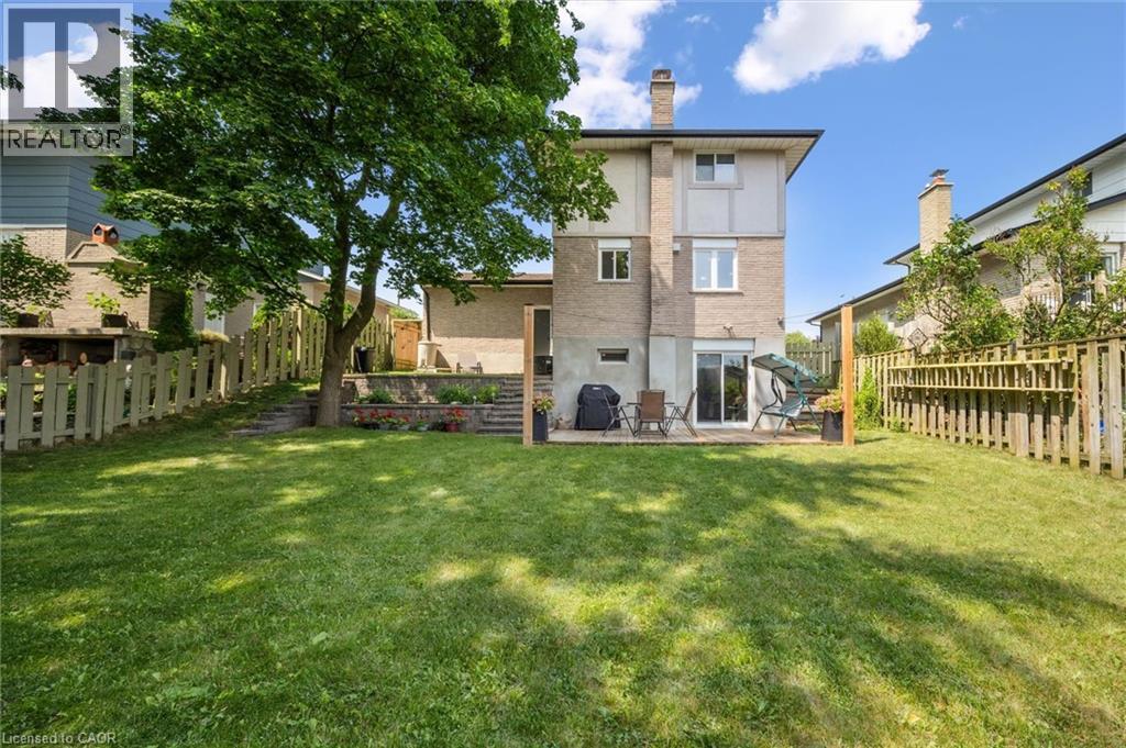 Spacious rear yard with a large grassy area, mature tree, and wood fencing