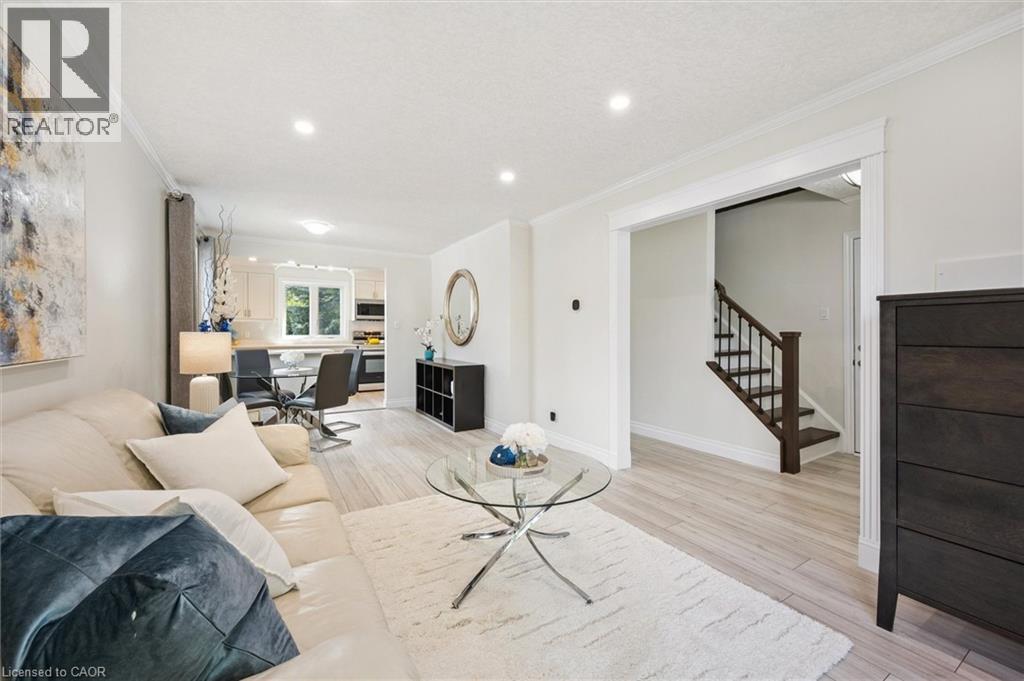 Spacious living area featuring light wood-finish flooring, recessed lighting, crown molding, and a white color palette