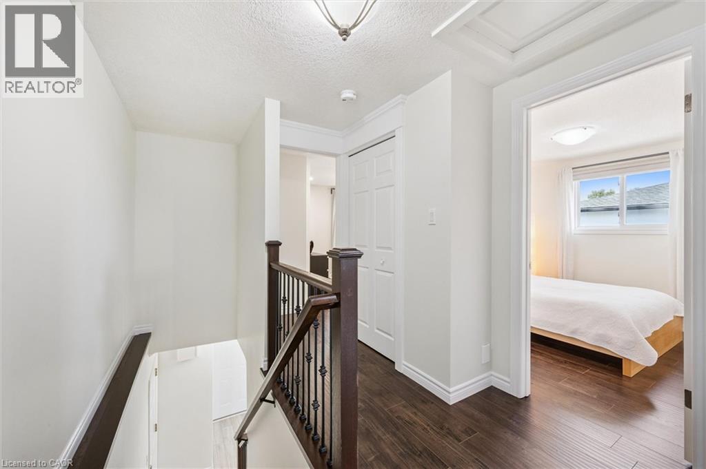 Upper-level landing featuring dark wood-finish flooring, white walls, and a staircase with dark wood handrails and black metal spindles