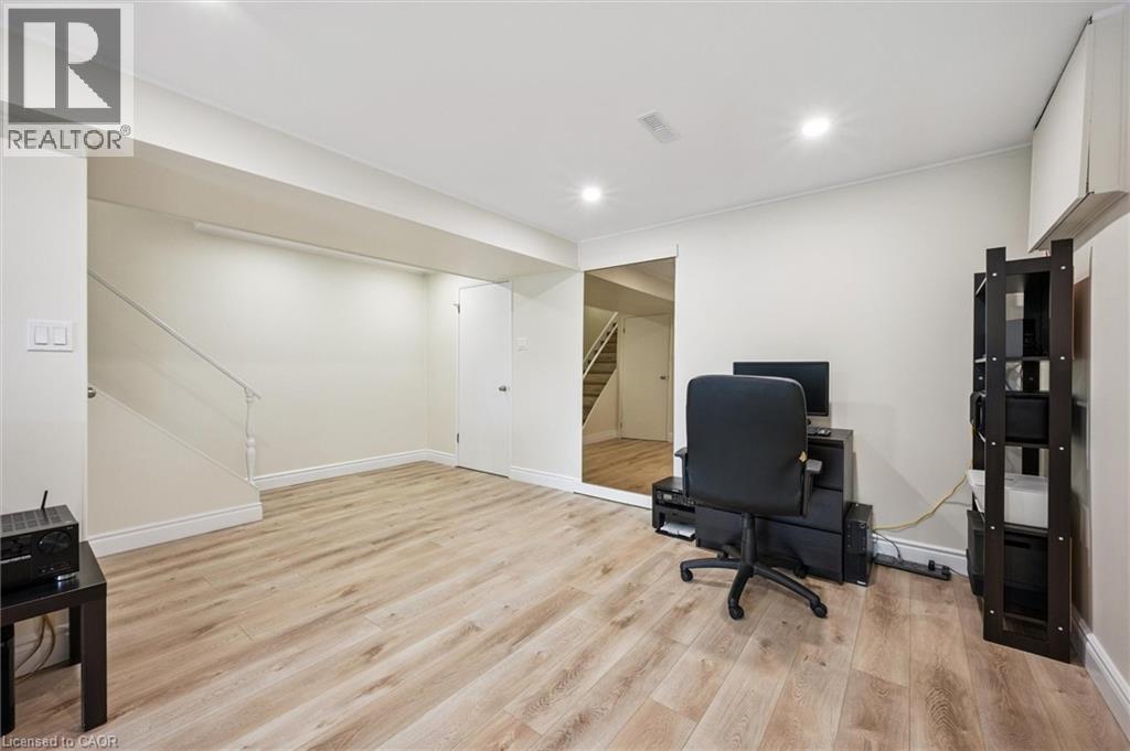 Open concept room featuring wood-finish flooring, recessed lighting, and a white painted staircase with a railing