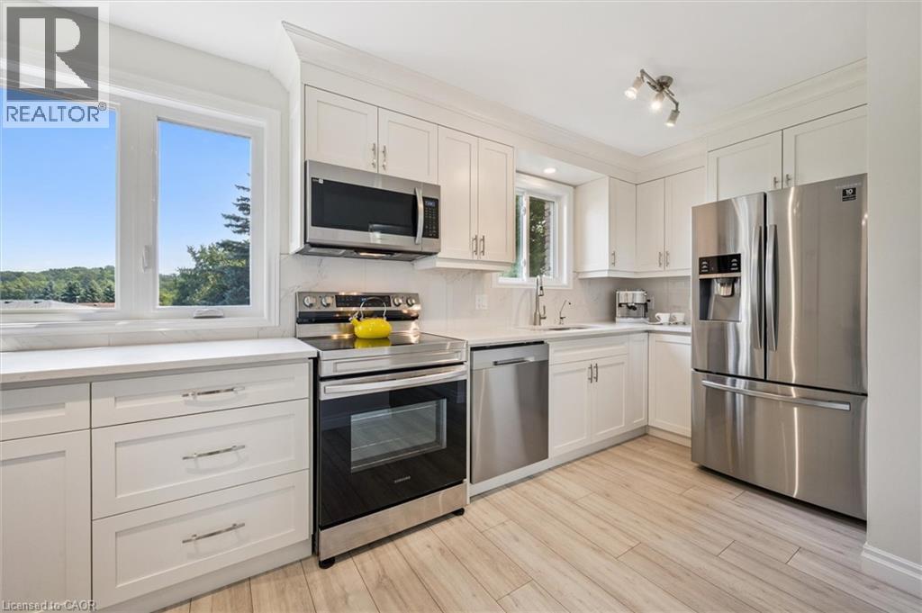 Kitchen featuring white cabinetry, stainless steel appliances, light-toned wood-finish flooring, white countertops, and a tile backsplash