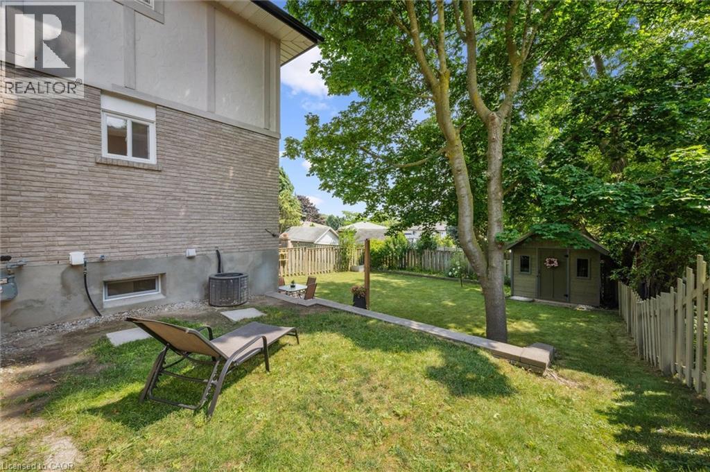 Spacious backyard featuring a manicured lawn, established trees, and a wooden storage shed